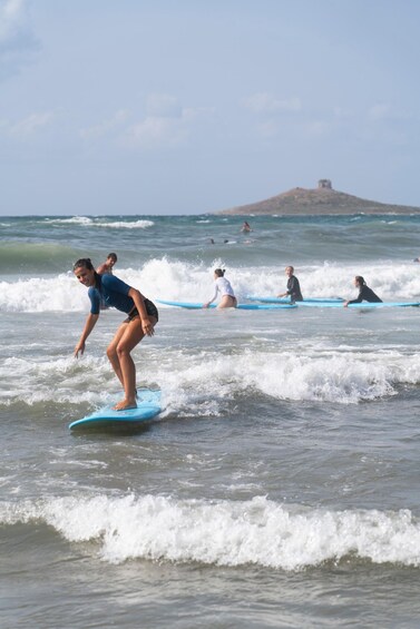 Surfere på blå surfbrætter i havet med bølger, og en fjern bakke. 2