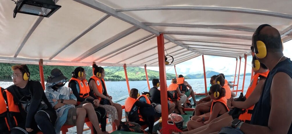 People on a boat wearing life jackets and ear protection. 3