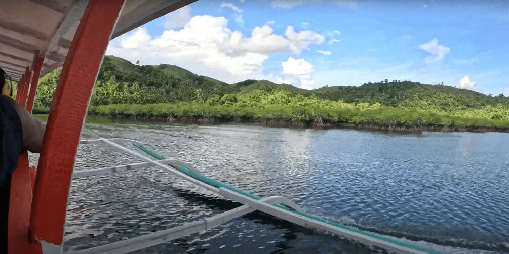 A river with a boat, surrounded by green hills and a partly cloudy sky. 2