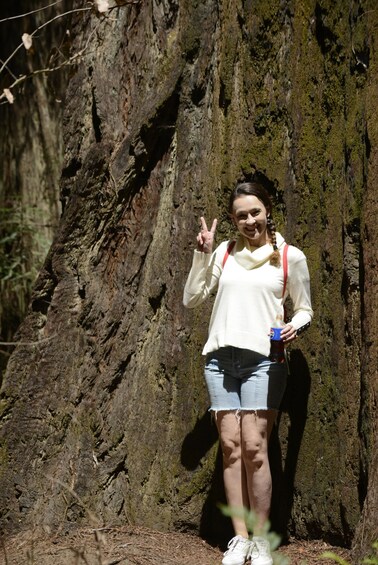 A person standing in front of a large tree with a backpack and a bottle. 3