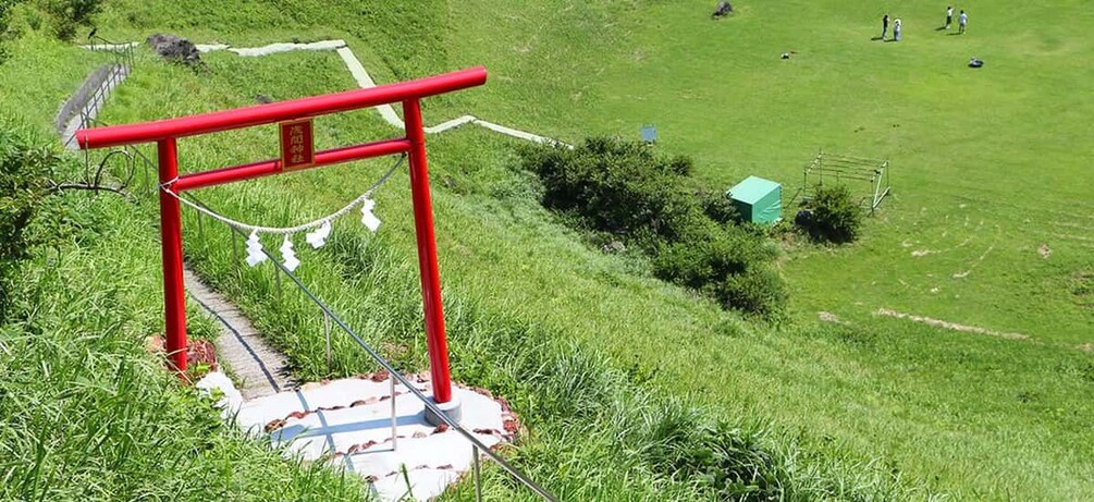 Un portón rojo en una colina cubierta de hierba, con un camino que sube hacia él. 3