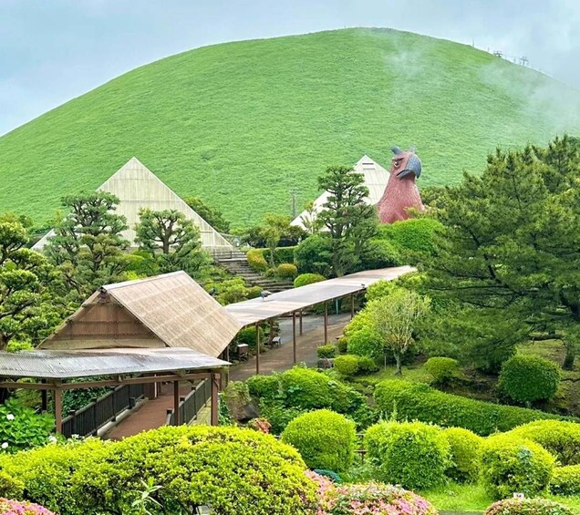 Un exuberante jardín con arbustos cuidadosamente recortados, una edificación tradicional japonesa y una gran estatua roja en una colina. 4