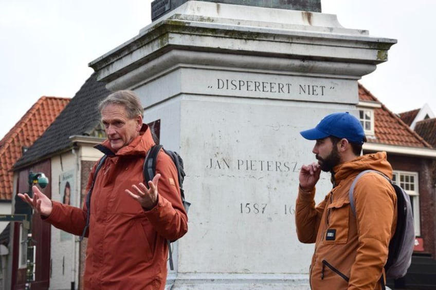 Two people standing in front of a monument with inscriptions. 1