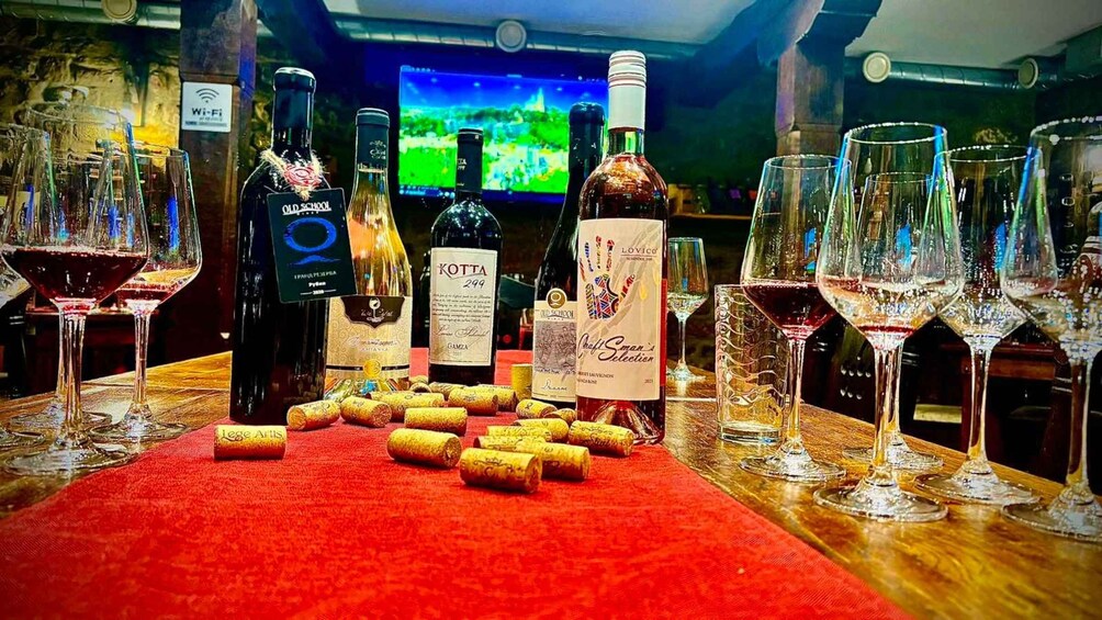 A bar setting with various bottles of alcohol, glasses, and corks on a red mat. 5