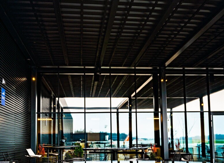 An indoor dining area with large windows, tables, chairs, and a view of a body of water. 3