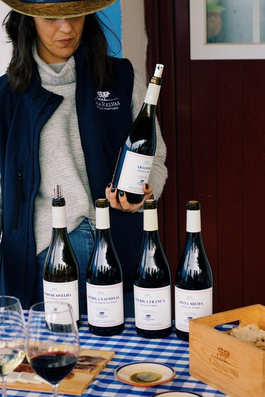 A person holding a bottle of Aragoné wine, with other bottles and glasses on a table. 4