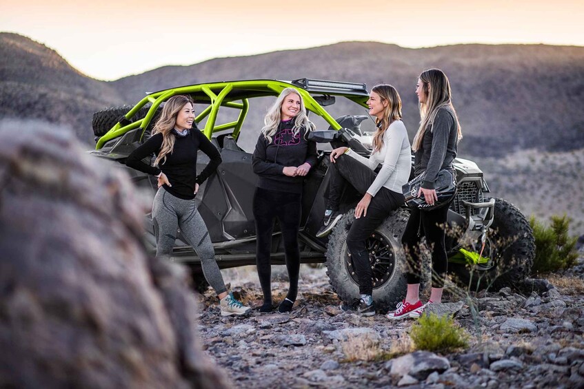 A group of people around a green off-road vehicle in a rocky outdoor setting. 5