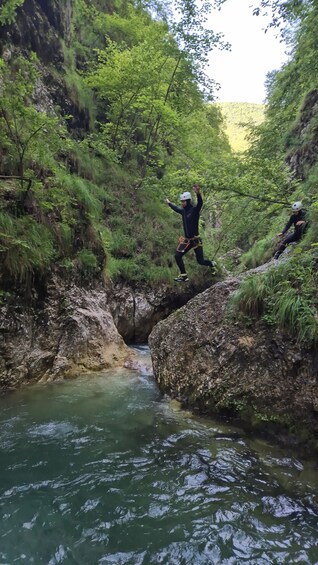 Two people rappelling down a rocky cliff into a river. 3