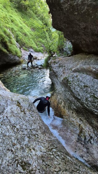 Zwei Personen seilen sich eine felsige Klippe hinab zu einem Fluss ab. 3