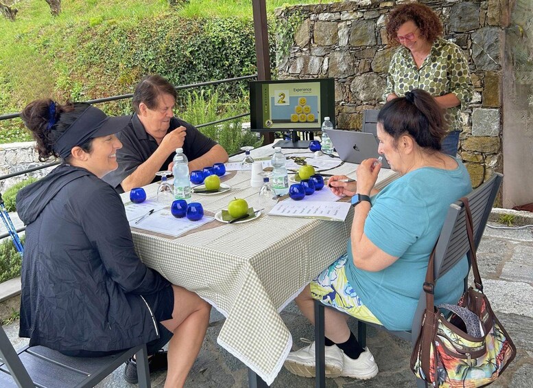 Four people sitting at an outdoor table with a laptop, papers, and water bottles. 1