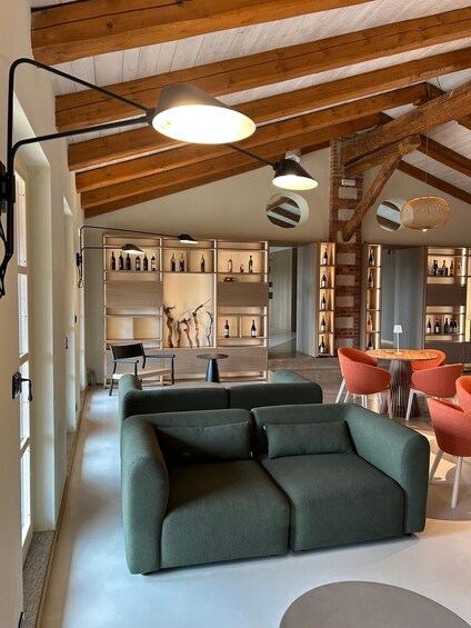 A modern living room with a green sofa, wooden beams, and wine racks. 3