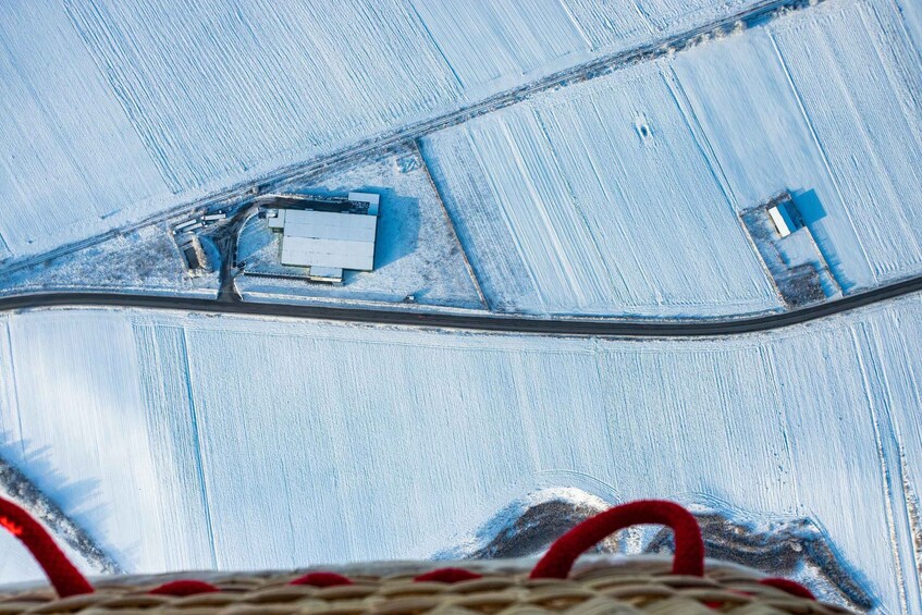 An aerial view of a snowy landscape with a road, buildings, and fields. 3