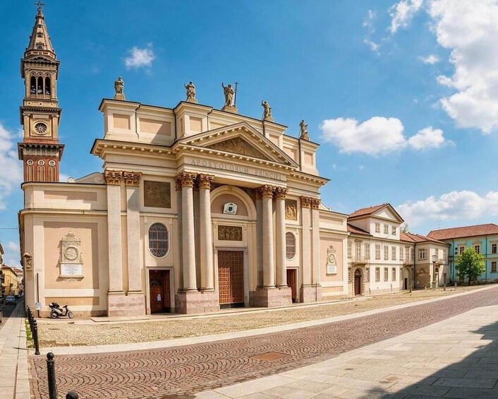 En historisk bygning med et tårn og et ur, klassisk arkitektur og en brostensbelagt gade. 5