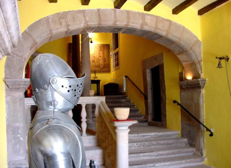 Eine Ritterstatue aus dem Mittelalter in einem gelbwandigen Raum mit einer Treppe. 4
