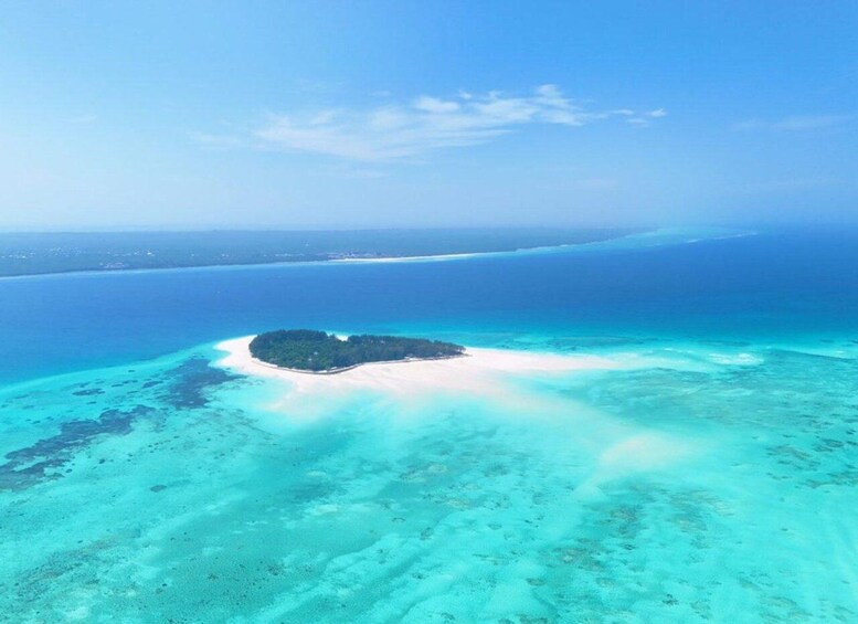 Eine Vogelperspektive auf ein türkisfarbenes Korallenriff mit einer kleinen Insel, umgeben von klarem, blauem Wasser. 3