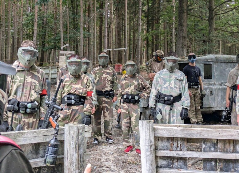 A group of people in camouflage uniforms and protective gear standing in a wooded area. 3