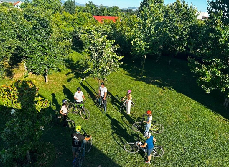 A group of people with bicycles on a grassy field surrounded by trees. 2