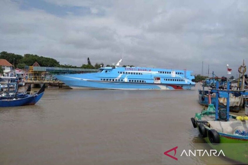 A large blue ferry docked at a port with smaller boats nearby. 1