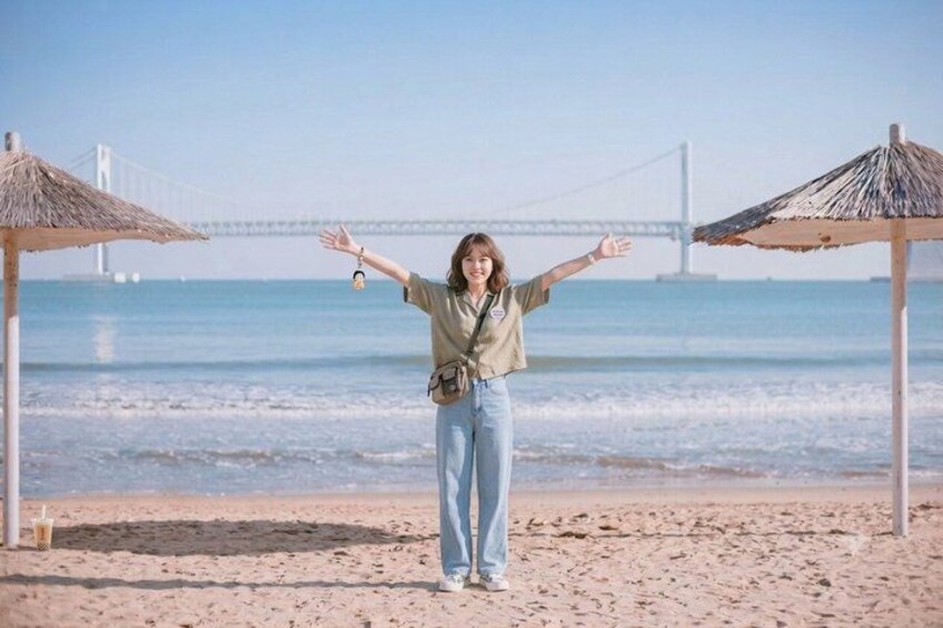 A person standing on a beach with a bridge in the background. 5