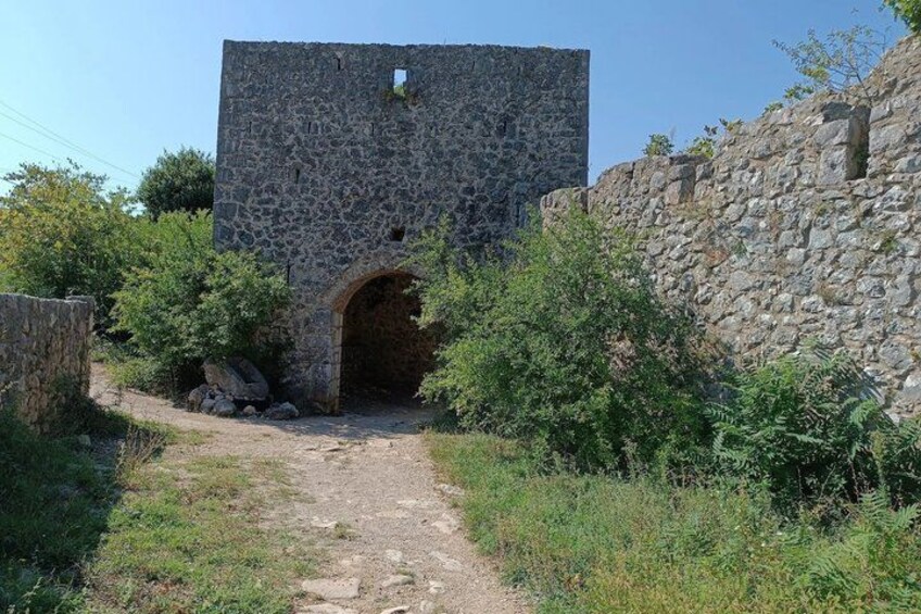 A stone archway leading to a stone building with a small window. 2