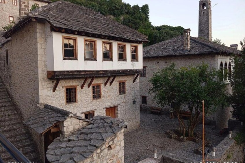 A stone building with a white facade, wooden windows, and a stone tower in the background. 5
