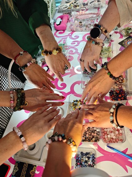 Un groupe de personnes tend les mains vers une table où sont disposés divers objets, notamment des perles et des bijoux. 5