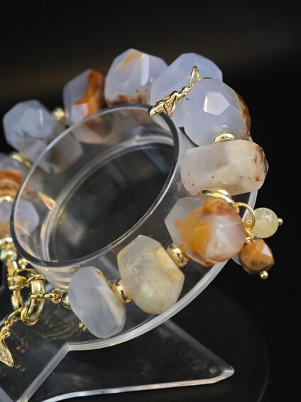 Un bracelet orné de pierres de différentes formes et couleurs, notamment des pierres blanches, brunes et transparentes, serties dans un métal de couleur or. 3