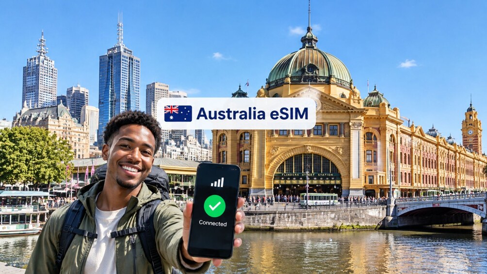 A person holding a smartphone with a connected eSIM in front of a historic building with a large dome and a clock tower. 1