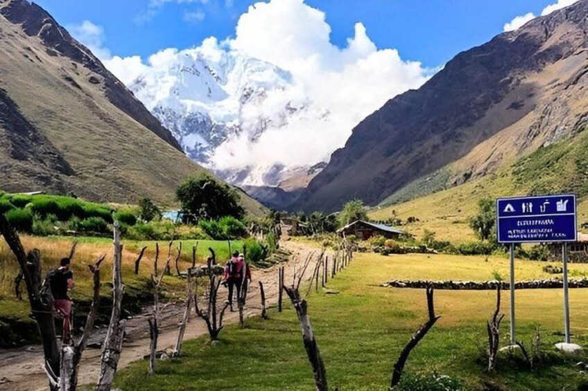 A mountainous landscape with a clear sky, a path with people walking, and a signpost. 4