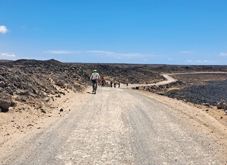 A group of cyclists on a gravel road in a barren landscape. 4
