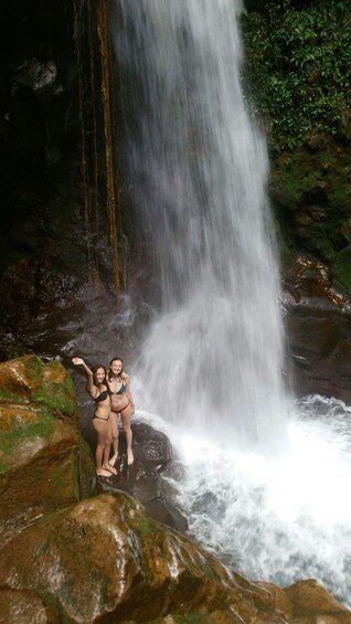 A waterfall with two people standing on rocks. 3