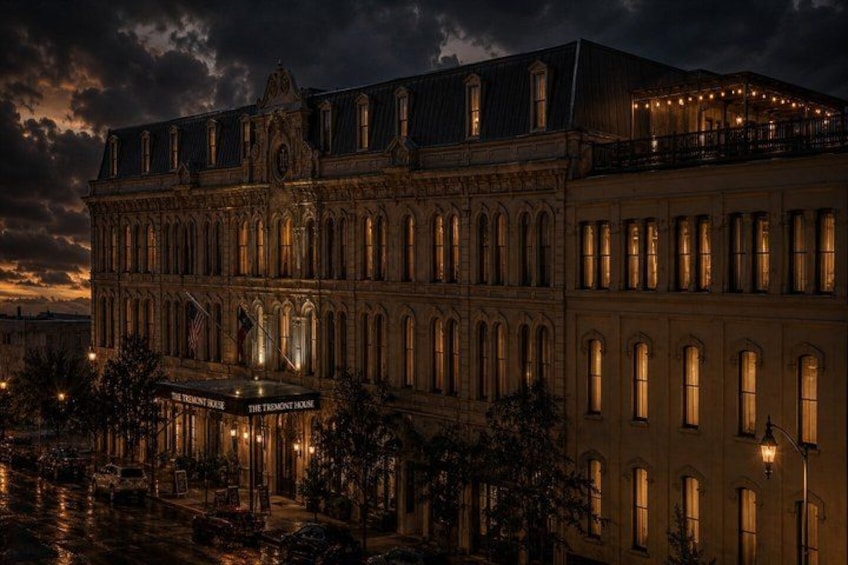 A historic building with arched windows and a balcony, illuminated by warm lights. 2