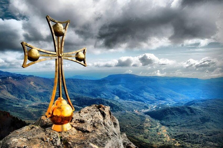 A golden cross on a rock with a mountainous landscape in the background. 4