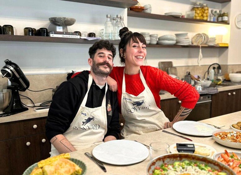 Two people in a kitchen with various dishes and cooking utensils. 1