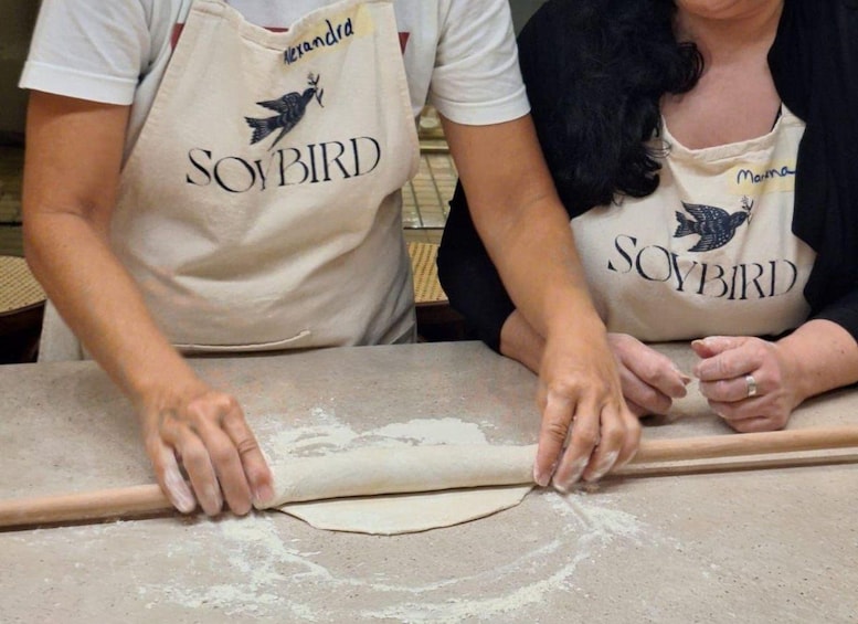 Two people rolling dough on a table. 2