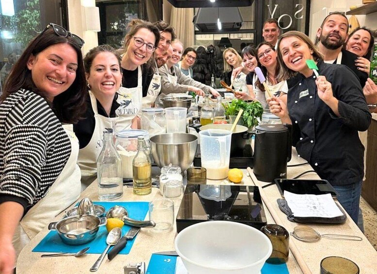 A group of people in a kitchen, some wearing aprons, with cooking utensils and ingredients on the counter. 3
