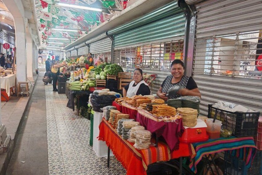 An indoor market with various stalls selling fruits, vegetables, and other goods. 3