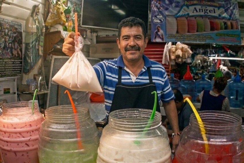 A person holding a plastic bag with a drink in a market setting. 5