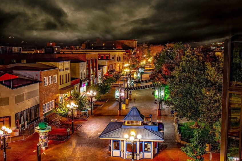 A nighttime view of a town square with illuminated buildings and street lamps. 4