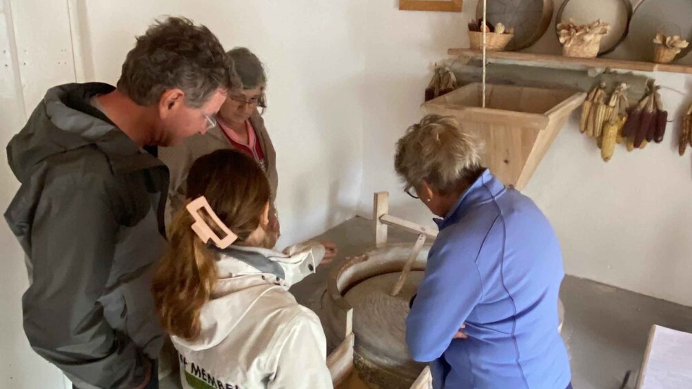 A group of people in a workshop with a wooden workbench and various tools hanging on the wall. 1