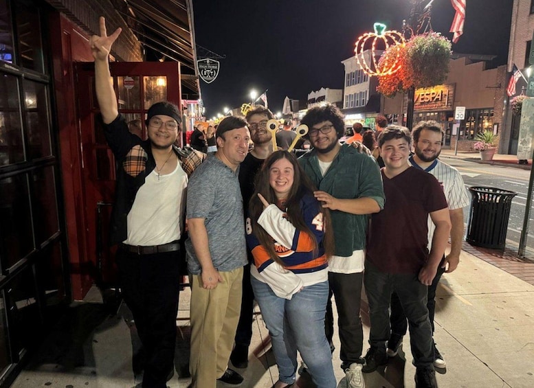 A group of people posing in front of a building with a sign that reads 'Hedge House.' 3