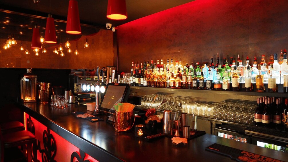 A bar with a variety of liquor bottles, glasses, and a cash register. 2
