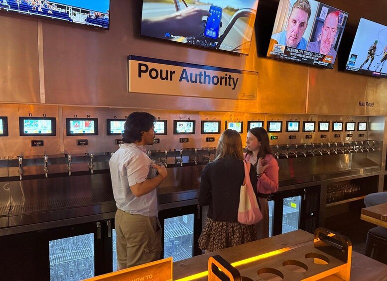 A bar area with multiple screens displaying content, a sign reading 'Pour Authority,' and a counter with numbered taps. 5