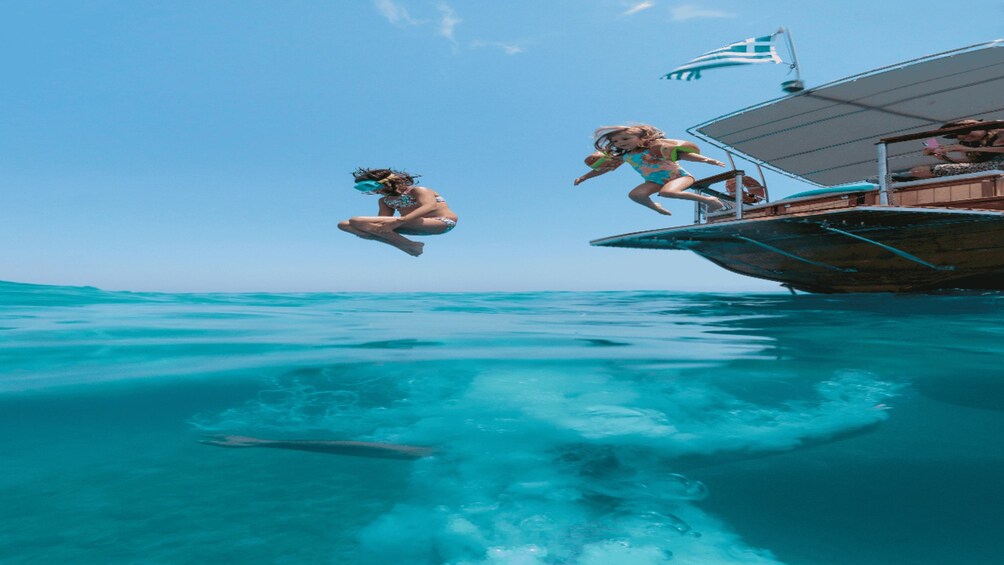 Two people jumping off a boat into the ocean. 2