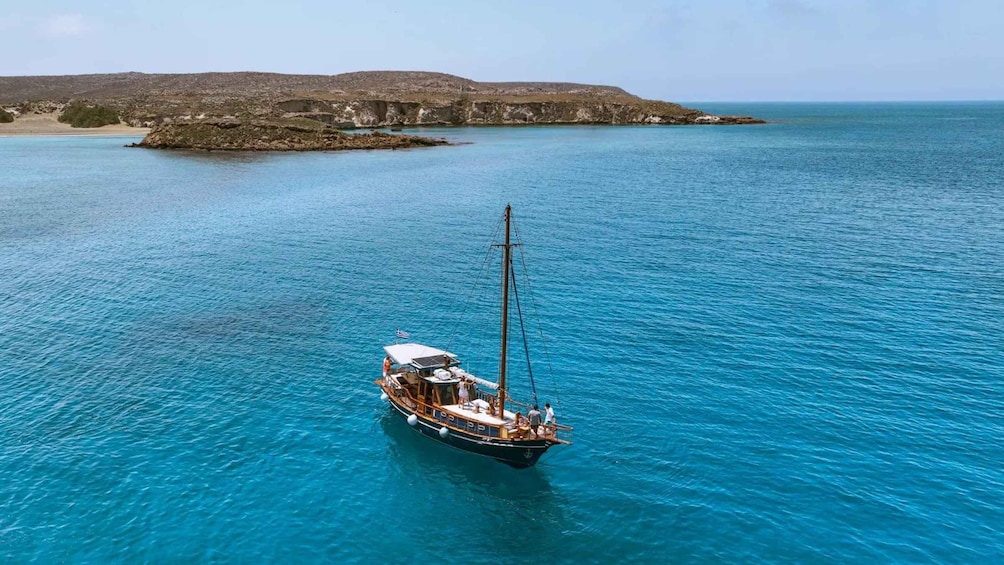 A sailboat in calm turquoise waters with a rocky island in the background. 5