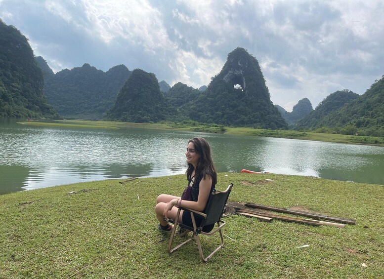 Une personne assise sur une chaise, près d’un lac, avec des montagnes en arrière-plan. 2