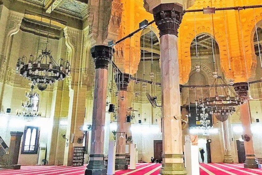 An interior of a large building with high ceilings, ornate columns, and chandeliers. 5