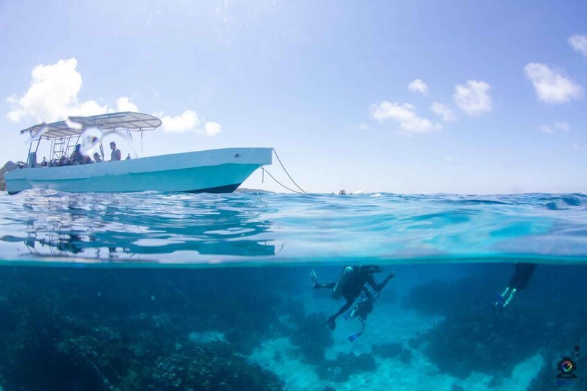 Un bateau avec des personnes à bord et deux plongeurs sous l’eau. 4