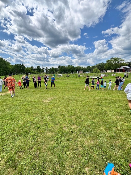 A group of people in a grassy field with a partly cloudy sky. 3