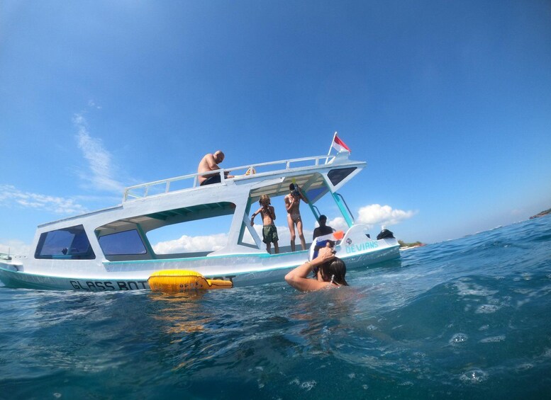 Ein Boot mit Personen an Bord, einige stehen, andere befinden sich im Wasser, über ihnen ein klarer, blauer Himmel. 5